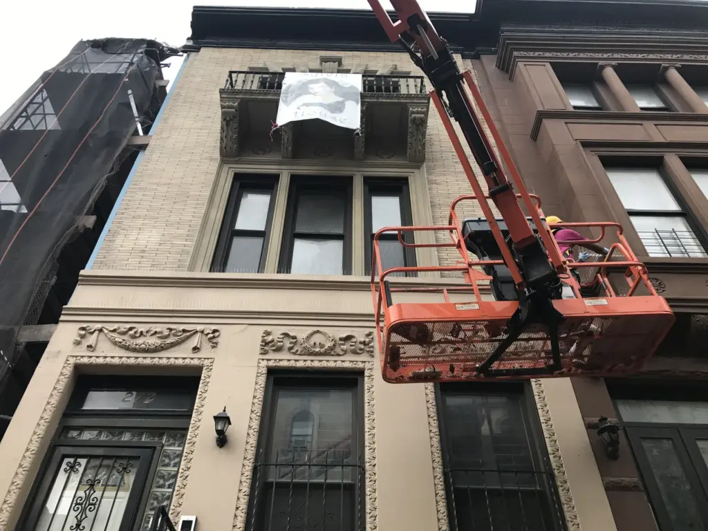 Power lift positioned for bird spike installation on a NYC building facade